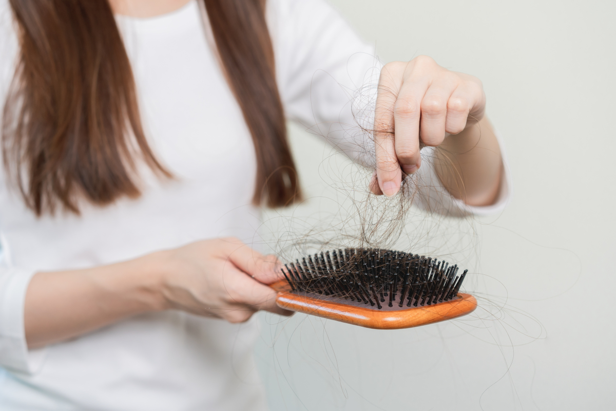 Person holding a hairbrush and pulling out tufts of hair