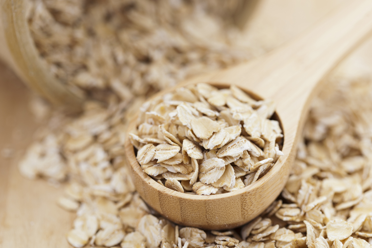 Holzlöffel mit Haferflocken liegt auf weiteren Haferflocken