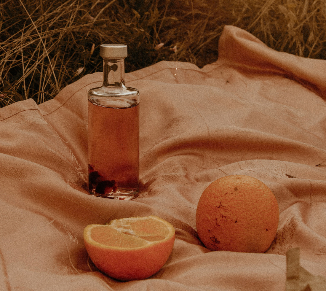 Grapefruit extract in a bottle, next to a whole and a halved grapefruit, on a cloth.