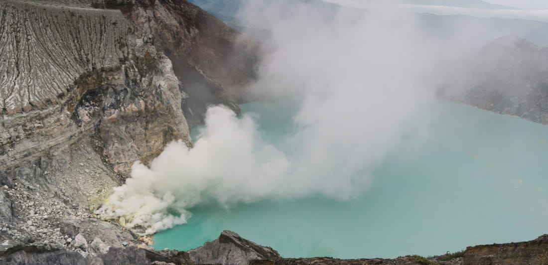 Lake surrounded by mountains, smoke.
