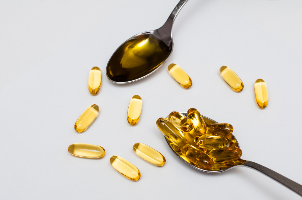 Softgelkapseln und Öl in einem Löffel.