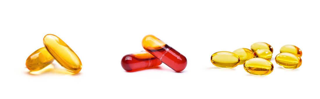 Verschiedene Kapseln vor weißem Hintergrund, in der Mitte mit rotem Krillöl gefüllt