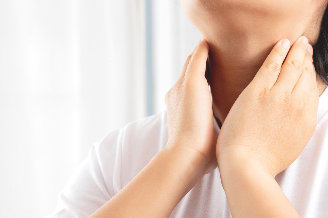 Person fasst sich an den Hals, wo die Schilddrüse liegt, Nahaufnahme.
