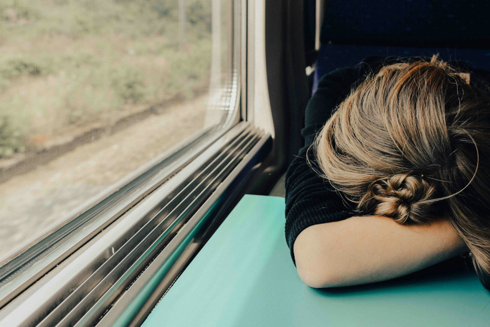 Person on a train with their head on the table.