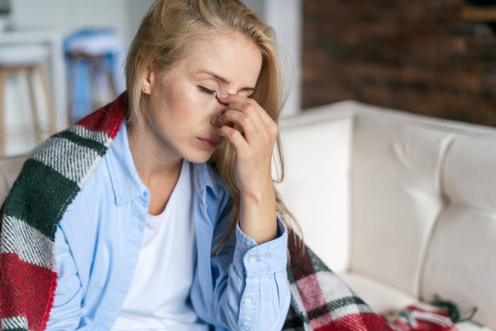 Person with a blanket over their shoulders, hand on their face.